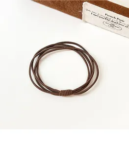 Détail d'un élastique à cheveux marron foncé à 4 brins montrant la texture tissée