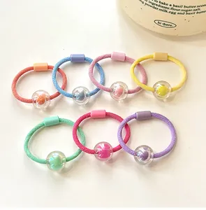 Detailed view of candy colored elastic hair ties with colorful pom-poms in clear beads