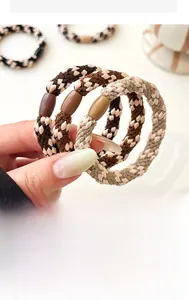 Close-up of thick elastic braided hair ties in earthy tones with decorative resin beads