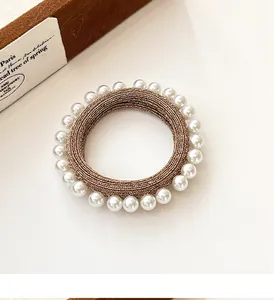 Détail d'un chouchou élastique marron champagne orné de perles blanches nacrées