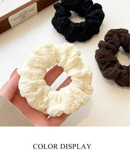 Three-piece set of puff scrunchies in black, white, and brown with pleated fabric texture