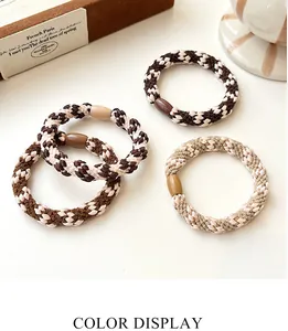 Detail of four thick woven hair ties in brown and beige tones with plastic buckles