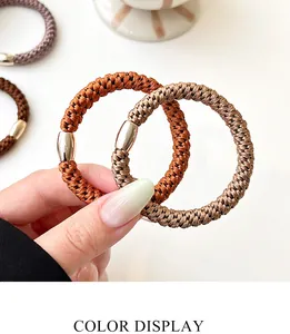 Detail of high-elastic braided hair ties with gold buckles in earthy brown colors