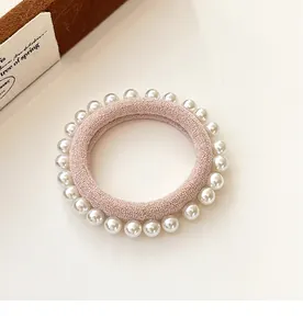 Vue détaillée d'un chouchou rose en tissu orné de perles blanches de haute qualité