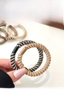 Close-up of woven high-elastic hair ties featuring gold thread and durable plastic clips