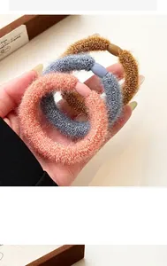 Detailed close-up of thick elastic plush hair ties in earthy brown, blue and coral colors