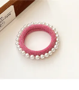 Gros plan sur l'élastique à cheveux rose avec perles blanches et texture brillante