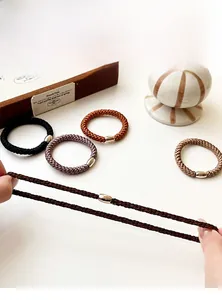 Detail view of woven high-elasticity hair ties with elegant golden metal beads decoration