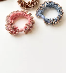 Detailed shot of elastic lace hair ties in pink, blue, and brown with gold trim edges