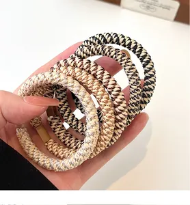Detail of five high-elasticity braided hair ties in milk coffee tones with matte clips
