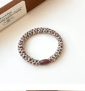 Detailed view of tri-color braided elastic hair ties with a smooth brown resin bead