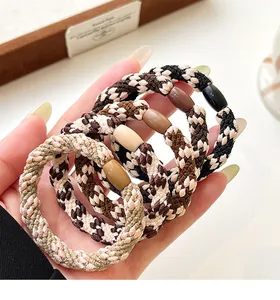 Close-up of four elastic braided hair ties in earth tones with houndstooth patterns