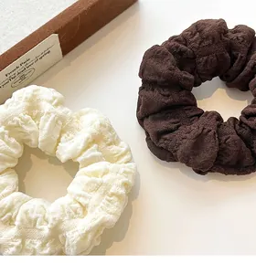 Detail of cream and dark brown puff fabric scrunchies with textured pleated finish