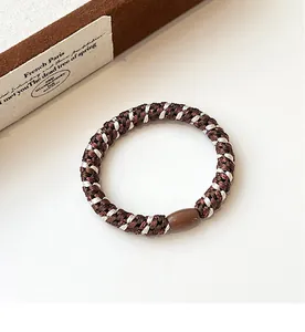 Detail of high-elasticity braided hair tie with a smooth brown oval resin bead accessory