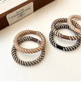 Close-up of thick braided hair ties with matching square buckles in earthy tones