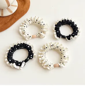 Close-up of four polka dot scrunchies in black and cream white with elegant ruffled edges