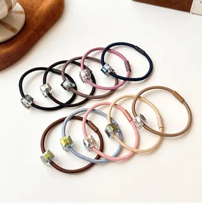 Close-up of Morandi colored elastic hair ties with rainbow crystal beads on white surface