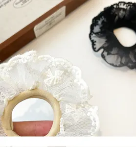 Macro detail of elegant double-layered lace hair scrunchies with embroidered bow details