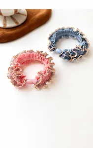 Detail of pink and blue lace hair scrunchies with scalloped gold edges and beads