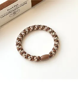 Detail of coffee and cream braided elastic hair tie with durable smooth resin connector