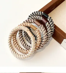 Detailed view of five high-elasticity woven hair ties in neutral earth tones and beige