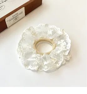 Close-up of white double-layered lace scrunchie with elegant scalloped edges and mesh texture