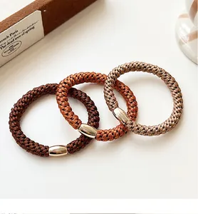 Detailed shot of three braided elastic hair ties with gold oval metal connectors