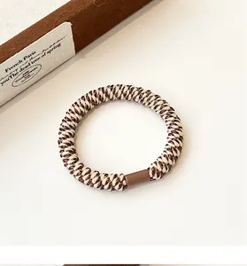 Detail of high-elasticity braided hair tie showing the coffee gold texture and connector