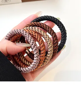 Detail of five thick elastic hair ties in neutral brown tones and woven texture