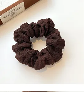 Detail shot of a dark brown French puff scrunchie with pleated fabric texture