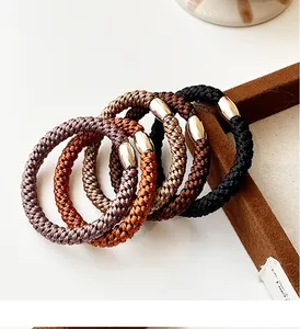 Close-up of five thick elastic hair ties in neutral earth tones with metallic buckles