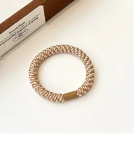 Macro detail of high-elasticity gold silk woven hair tie with retro brown buckle