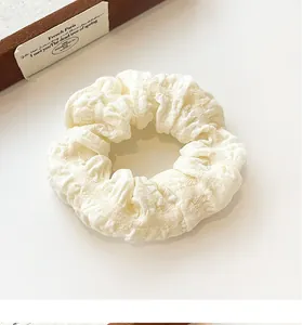 Close-up of beige puff scrunchie showing detailed puckered fabric texture and soft finish