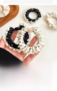 Close-up of polka dot ruffle hair scrunchies in black and white fabric held by hand