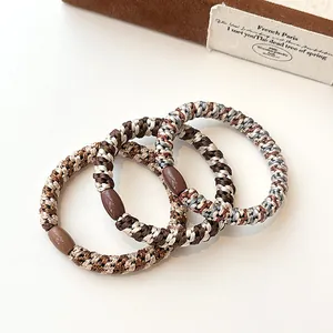 Three-pack elastic braided hair ties in coffee and neutral tones with oval buckles