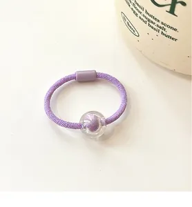 Detail of high-elasticity purple beaded hair tie with clear sphere and pom-pom charm