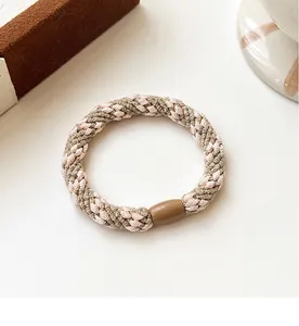 Close-up of thick woven elastic hair tie in pink and taupe with polished brown resin clasp