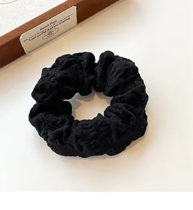 Detailed close-up of a black puffy scrunchie featuring high-elasticity seersucker fabric