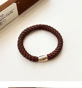 Detailed view of deep brown elastic hair tie with a polished gold metallic cylinder bead