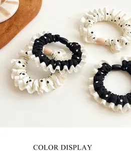 Close-up of polka dot pattern scrunchies with pleated lace edges and oval buckles