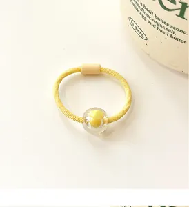 Macro view of bright yellow high-elasticity hair tie with candy-colored bead detail
