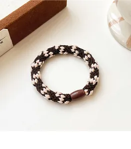 Detail of woven checkerboard hair tie in brown and beige with thick elastic texture