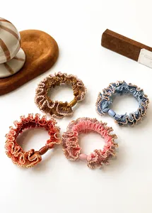Detailed shot of four elastic lace scrunchies in autumn tones with golden scalloped edges