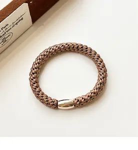 Close-up of thick brown elastic hair tie with a decorative gold oval metal bead