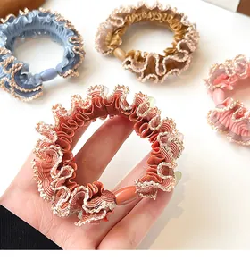 Detailed view of elastic ruffled hair scrunchies with lace trim in four soft pastel colors