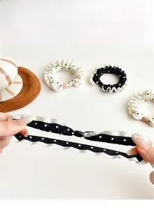 Detail of polka dot scrunchie with lace edges and elastic band on white desk