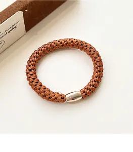 Detail of hand-woven high elasticity hair tie with polished silver metal fastener
