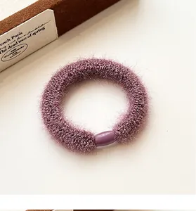 Detail of purple plush hair tie with shiny fiber texture and smooth oval buckle link