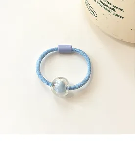 Detail of light blue elastic hair tie with transparent bead and purple buckle accents