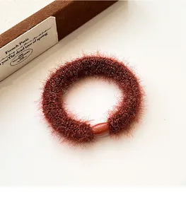 Detail of red-brown plush elastic hair tie with round glossy clasp on vintage box